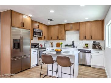 Bright kitchen with stainless steel appliances, wood cabinets, island, and white countertops at 1116 E Owens Ave, North Las Vegas, NV 89030