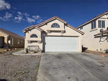 Charming single-story home with a two-car garage, tile roof, desert landscaping, and sunny skies at 3512 Trilogy Dr, Las Vegas, NV 89108