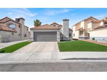 Charming home featuring a 2-car garage, red tile roof, and well-maintained artificial lawn at 5762 Yerington Ave, Las Vegas, NV 89110