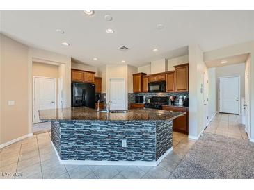 Bright kitchen features a central island with mosaic tile and granite countertop at 10693 Harvest Green Way, Las Vegas, NV 89135
