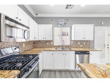 Well-lit kitchen featuring white cabinets, granite countertops, stainless steel appliances, and a mosaic backsplash at 3532 Carisbrook Dr, North Las Vegas, NV 89081