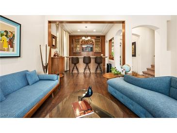 Open-concept living room features a bar, hardwood floors and two stylish sofas at 5850 Rockway Glen Ave, Las Vegas, NV 89141