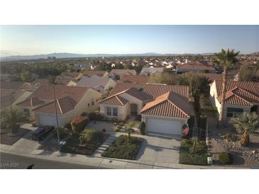 An aerial view showcases a charming home with a red tile roof in a well-maintained, lushly landscaped neighborhood at 10717 Grand Cypress Ave, Las Vegas, NV 89134