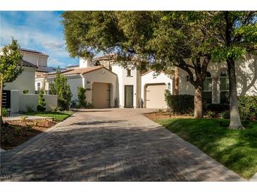 Elegant single-story home featuring a brick driveway and a symmetrical facade with two garage doors at 11830 Kingsbarns Ct, Las Vegas, NV 89141