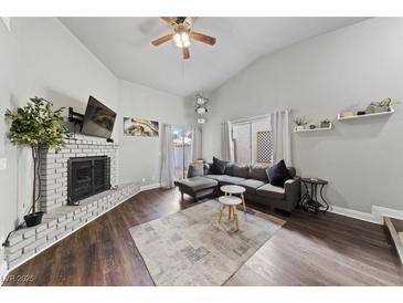 Inviting living room with a painted brick fireplace, wood floors, and vaulted ceiling at 504 Crony Ave, Henderson, NV 89011