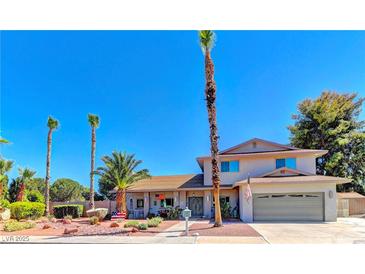 Charming two-story home with a well-manicured yard and mature palm trees under a bright blue sky at 893 Fairway Dr, Boulder City, NV 89005