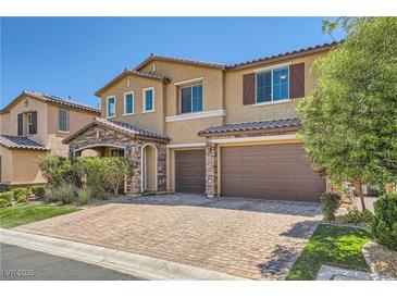 Inviting two-story home featuring stone accents, a brick driveway, and a two-car garage at 12296 Kings Eagle St, Las Vegas, NV 89141