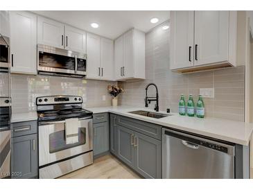 Updated kitchen with stainless steel appliances, white quartz countertops, and modern gray backsplash at 5020 Village Dr, Las Vegas, NV 89142