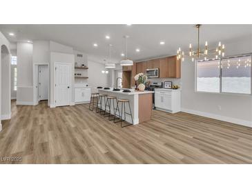 Bright kitchen features an island with seating, modern light fixtures, and stainless steel appliances at 10886 Porto Foxi St, Las Vegas, NV 89141