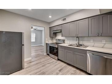 Modern kitchen featuring gray cabinets, stainless steel appliances, and wood-look flooring at 155 Magnesium St, Henderson, NV 89015