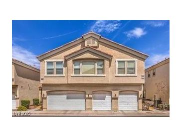 Beige two-story home with three-car garage and well-maintained landscaping at 1612 Lefty Garcia Way, Henderson, NV 89002