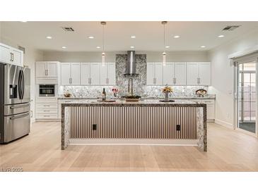 Spacious kitchen with white cabinetry, stainless steel appliances, and a large center island with granite countertop at 2372 Perrysburg Dr, Henderson, NV 89044