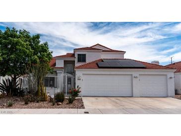 Two-story home with a white exterior, red tile roof, three-car garage, and a well-manicured front yard at 3008 Blue Fin Cir, Las Vegas, NV 89128