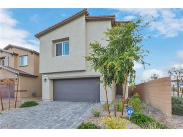 Two story home featuring a gray garage door, neutral stucco, and manicured landscaping at 816 Sand Camel Ct, North Las Vegas, NV 89081