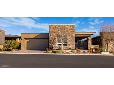 Contemporary home featuring a stone facade, well-manicured landscaping, and a two-car garage at 9858 Gemstone Sunset Ave, Las Vegas, NV 89148
