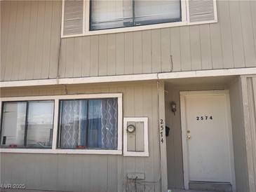 Two-story townhouse featuring neutral siding, a front door, and visible window details at 2574 Paradise Village Way, Las Vegas, NV 89120