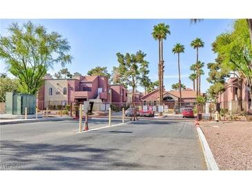 Gated community entrance featuring brick buildings, mature landscaping, and ample parking at 4050 Pacific Harbors Dr # 107, Las Vegas, NV 89121
