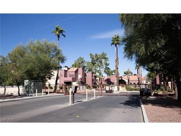 Gated community entrance with mature landscaping and palm trees under a clear blue sky at 4050 Pacific Harbors Dr # 245, Las Vegas, NV 89121