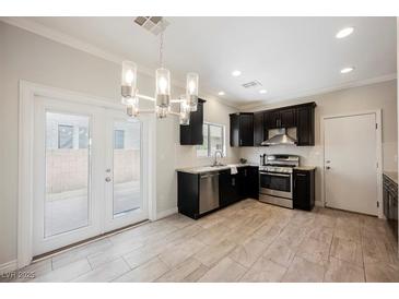 Bright eat-in kitchen features stainless appliances, dark cabinetry, and stylish chandelier lighting at 5439 Bradford Pear Dr, Las Vegas, NV 89122