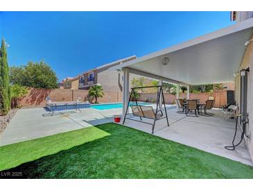 Inviting backyard features a sparkling pool, covered patio, and lush green lawn for relaxation and enjoyment at 9656 Paraiso Springs St, Las Vegas, NV 89139