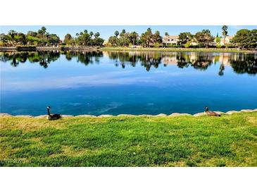 Beautiful lake view with lush greenery and clear reflections of the homes across the water at 2529 Seascape Dr, Las Vegas, NV 89128