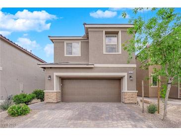 Two-story home featuring neutral stucco, stone accents, a two-car garage, and a paved driveway at 10029 Cluny Ave, Las Vegas, NV 89178