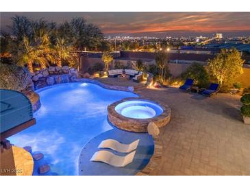 Resort-style pool boasts a rock waterfall, jacuzzi, tanning ledge, and fire pit seating area, with city views at 10084 Terrastone Dr, Las Vegas, NV 89148