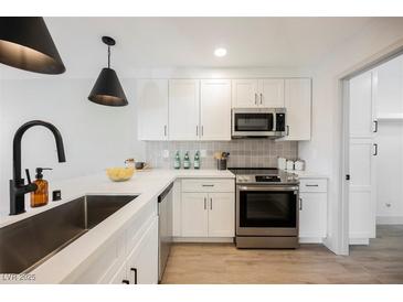 Well-lit kitchen features stainless steel appliances, white cabinets, and sleek black fixtures at 1800 Edmond St # 115, Las Vegas, NV 89146