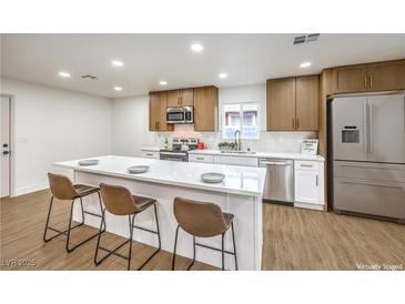 Modern kitchen featuring an island with seating, stainless steel appliances, and wooden cabinets at 2536 Herrod Dr, North Las Vegas, NV 89030