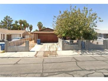 Single-story home with a spacious driveway and a well-maintained concrete and iron fence and a mature shade tree at 408 Rhoda St, Las Vegas, NV 89110