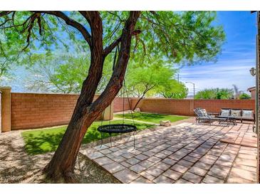 Well-kept backyard with a charming patio, green space and mature tree at 10220 Adobe Mountain St, Las Vegas, NV 89178