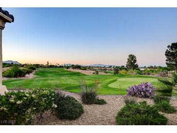 Scenic view of the golf course with lush green grass, desert landscaping, and beautiful mountain views in the background at 10562 Cerotto Ln, Las Vegas, NV 89135