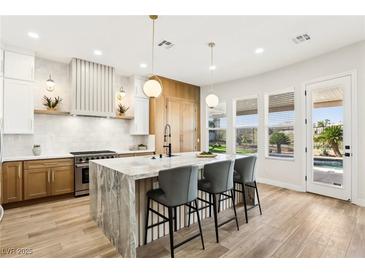 Modern kitchen with a marble island, stainless steel appliances, and an open view to the backyard pool at 1343 Panini Dr, Henderson, NV 89052