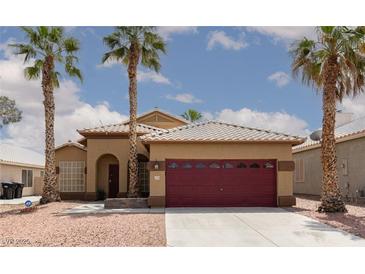 Charming single-story home with desert landscaping, palm trees and a red two car garage door at 1723 Anchor Dr, North Las Vegas, NV 89032