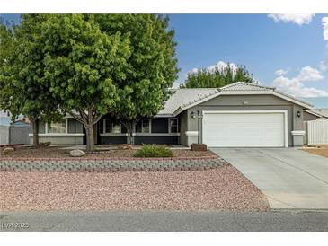 Charming home featuring a well-maintained front yard, a large tree, and a two-car garage at 5200 Wheatland Dr, Pahrump, NV 89061