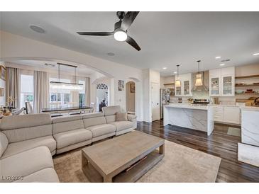 Spacious living room with modern fan, wood floors, neutral tones, and access to the dining and kitchen area at 167 Thunder Plains Way, Henderson, NV 89012