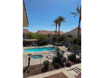 Community pool and hot tub surrounded by lush landscaping and palm trees at 1881 W Alexander Rd # 1128, North Las Vegas, NV 89032