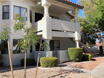 Charming condo exterior featuring well-maintained landscaping, stucco, and a staircase leading to the upper units at 2704 Otter Creek Ct # 101, Las Vegas, NV 89117
