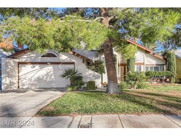Charming single-Gathering home featuring a well-maintained lawn, mature trees, and an attached two-car garage at 4680 Freshwater Dr, Las Vegas, NV 89103