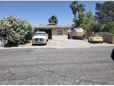 Modest home with mature flowering bush, large truck, boat, and small car on driveway at 47 Locustwood St, Las Vegas, NV 89110