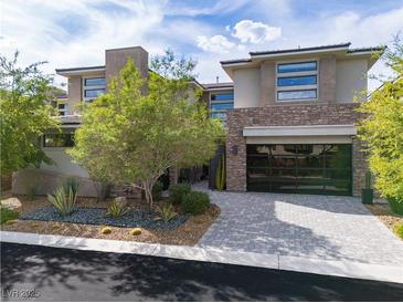 Stunning two-story home featuring a modern design, stone accents, glass garage door and beautifully landscaped front yard at 5 Moonfire Dr, Las Vegas, NV 89135