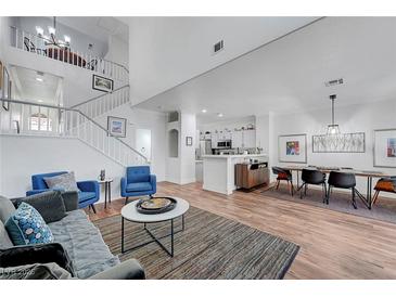 Open-concept living room featuring a staircase, modern decor, and a dining area adjacent to the kitchen at 5221 Tropical Peach Dr, Las Vegas, NV 89118