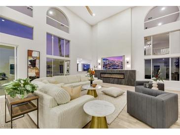 Bright living room with high ceilings, large windows, modern fireplace, and stylish decor with hardwood flooring throughout at 62 Incline Village Ct, Henderson, NV 89074