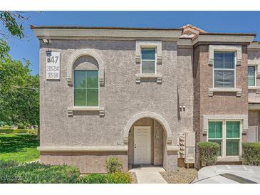 Two-story townhome featuring stucco exterior, arched entryway, and well-maintained landscaping at 10001 Peace Way # 2335, Las Vegas, NV 89147