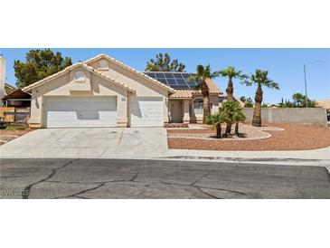 Charming single-story home featuring a two-car garage, solar panels, and desert landscaping with palm trees at 6328 Yankee Meadow Cir, Las Vegas, NV 89130