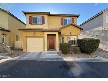 Two-story home with a two car garage, charming red front door, and manicured landscaping at 6777 Wormwood Ln, Las Vegas, NV 89148