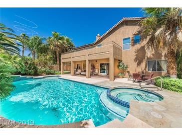 Inviting backyard oasis featuring a sparkling pool, spa, covered patio, and lush landscaping at 7751 Locke Haven Dr, Las Vegas, NV 89123