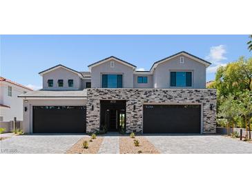 Striking two-story home featuring stone accents, a three-car garage, and desert landscaping at 8721 Robinson Ridge Dr, Las Vegas, NV 89117