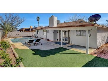 This backyard features a sparkling pool, artificial turf, and a covered patio, perfect for outdoor relaxation and entertaining at 976 El Camino Way, Boulder City, NV 89005