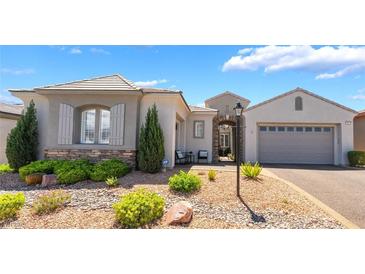 Charming single-story home featuring a stone facade, manicured landscaping, and a two-car garage at 10579 Garden Rose Dr, Las Vegas, NV 89135